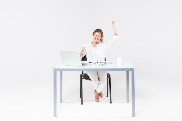 Celebrazione della donna di affari allo scrittorio con il computer portatile isolato su fondo bianco