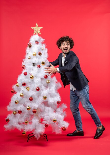 celebrazione di natale con giovane uomo divertente eccitato felice che abbraccia l'albero di Natale