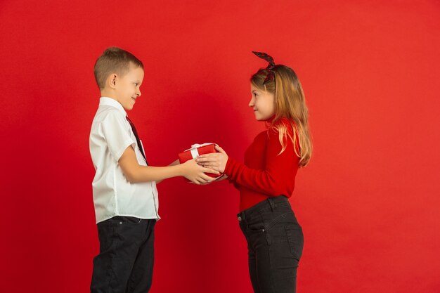 Celebrazione di San Valentino, bambini caucasici felici isolati su priorità bassa rossa