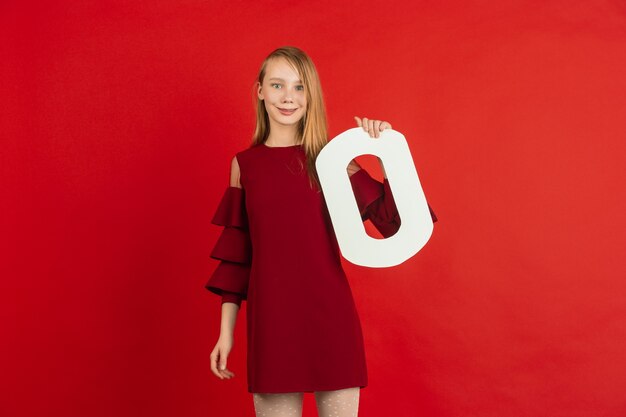 Celebrazione di San Valentino, felice, carina ragazza caucasica che tiene la lettera su sfondo rosso studio.