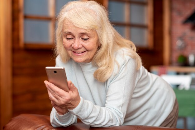 Cellulare di sguardo femminile senior di angolo basso