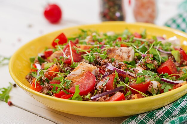 Cena salutare. Pranzo insalatiera con pollo grigliato e quinoa, pomodoro, peperoni, cipolle rosse e rucola