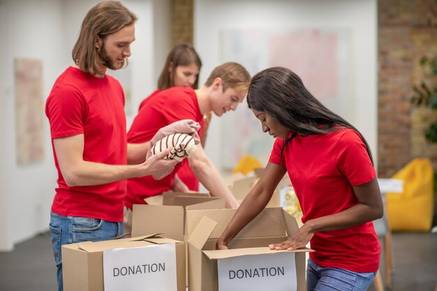 Centro di smistamento. Giovani volontari in magliette rosse che distribuiscono donazioni in un centro di smistamento