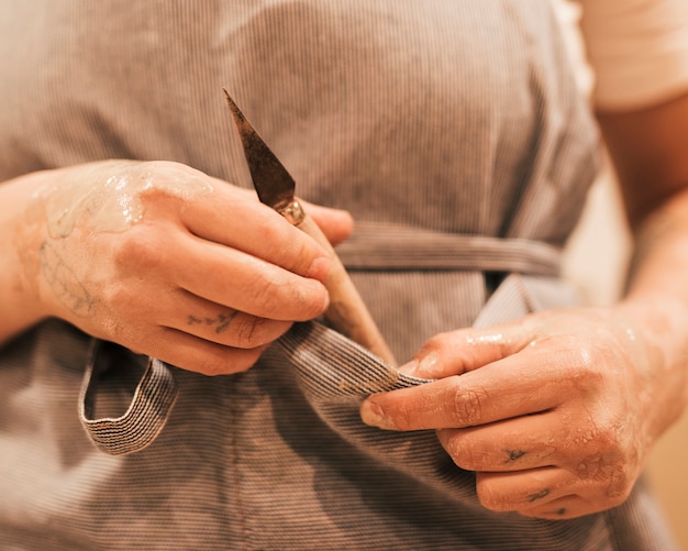 Ceramista che tiene in mano uno strumento da intaglio dalla tasca