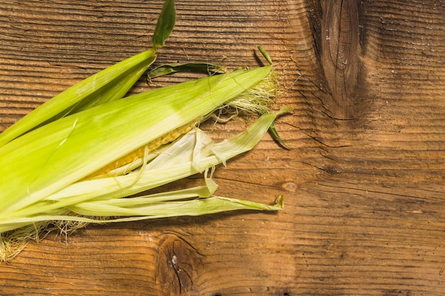 Cereale fresco sulla pannocchia contro fondo di legno