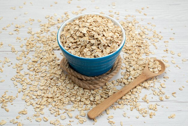 Cereali crudi di vista superiore su bianco, con il pasto crudo dell'alimento di prima colazione del cucchiaio