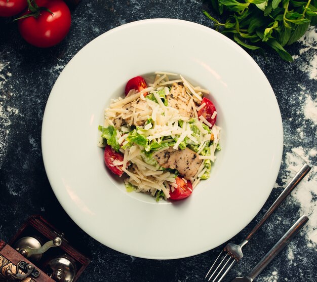 Cesare con formaggio tritato, erbe e pomodori.