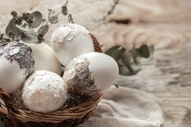 Cestino con uova e fiori secchi su uno sfondo sfocato. Un'idea originale per decorare le uova di Pasqua.