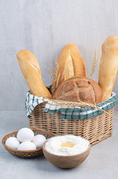 Cestino del pane, uova e farina sulla superficie della pietra