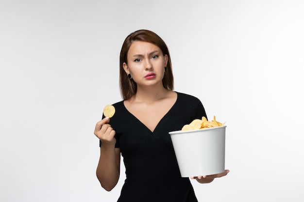 Cestino femminile giovane della tenuta di vista frontale con le patatine fritte sulla superficie bianca chiara