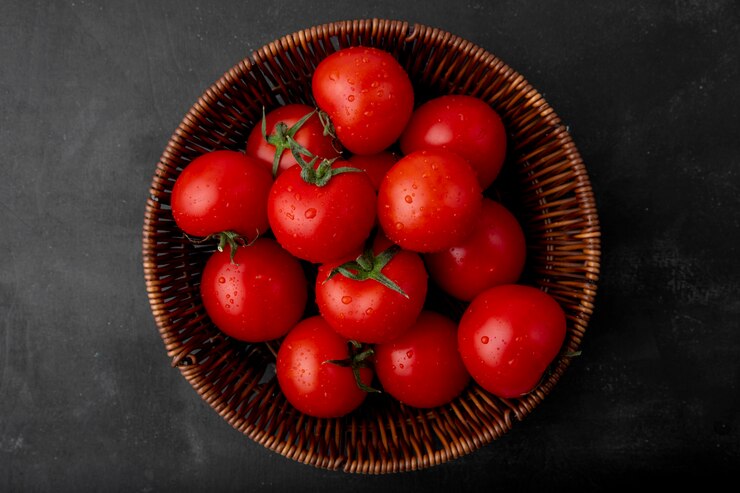 Foto gratuito cesto di pomodori sulla superficie nera