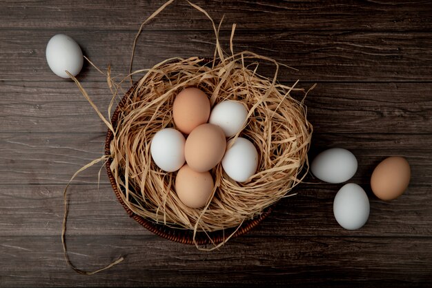 cesto di uova nel nido con uova intorno sul tavolo di legno