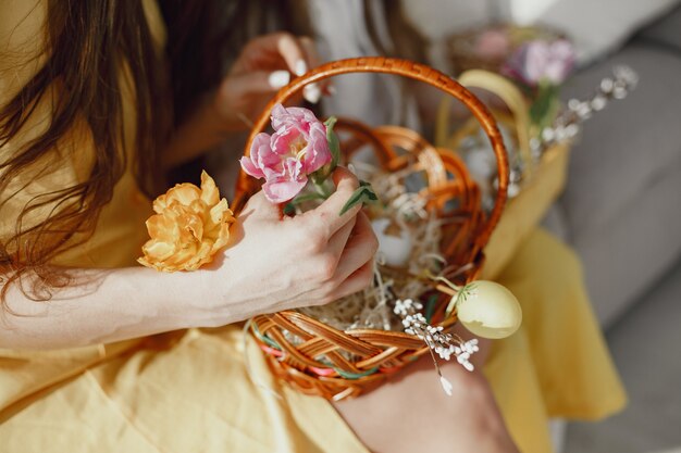 Cesto festivo di Pasqua nelle mani di una donna in un vestito giallo