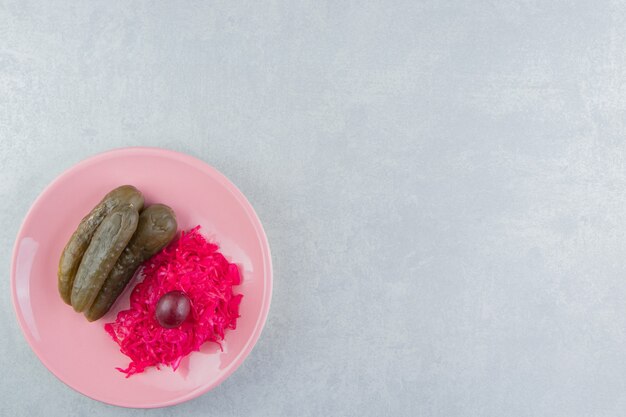 Cetrioli e cavoli fermentati sul piatto rosa.