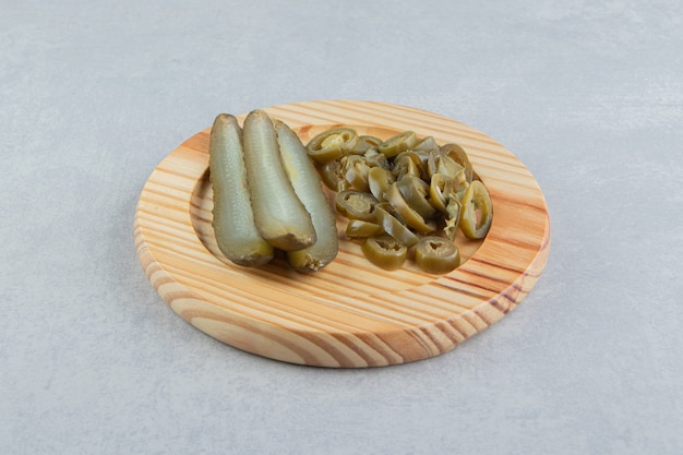 Cetrioli e peperoni sott'aceto sul piatto di legno.