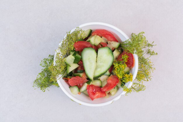 Cetrioli e pomodori a fette in una ciotola bianca con verdure