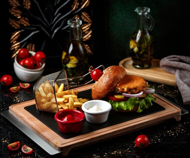 Cheeseburger con patatine fritte su tavola di legno