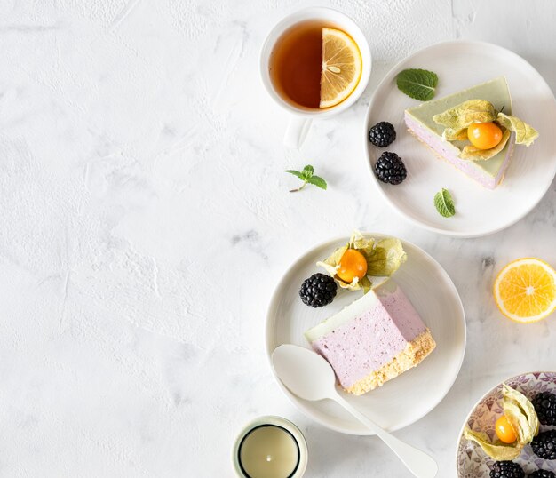 Cheesecake al cocco a fette con tè matcha giapponese, cioccolato bianco e frutti di bosco su un tavolo bianco Vista dall'alto