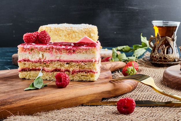 Cheesecake alla fragola con un bicchiere di tee su una tavola di legno.