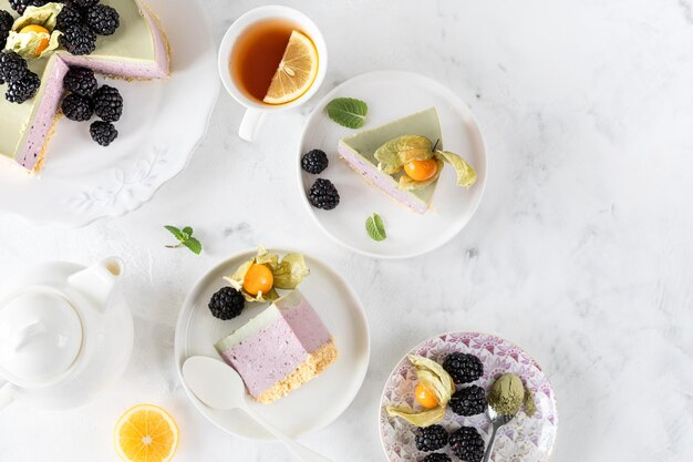 Cheesecake fatta in casa senza pasticcini alle more e tè matcha sul tavolo festivo Pezzi di dessert ai frutti di bosco a fette Vista dall'alto Spazio di copia