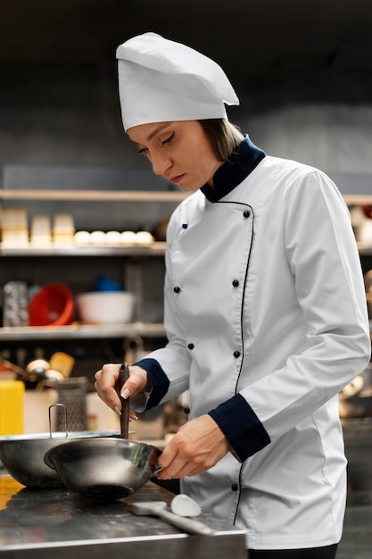 Chef che cucina in cucina indossando abiti professionali