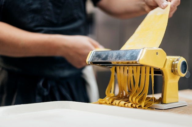 Chef con grembiule utilizzando macchina per affettare la pasta
