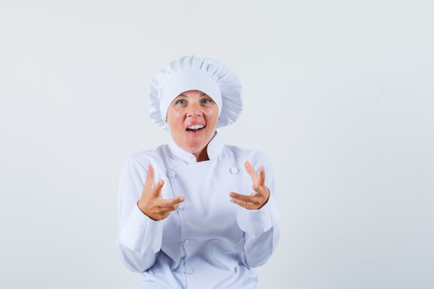 chef donna alzando le mani in uniforme bianca e guardando eccitato