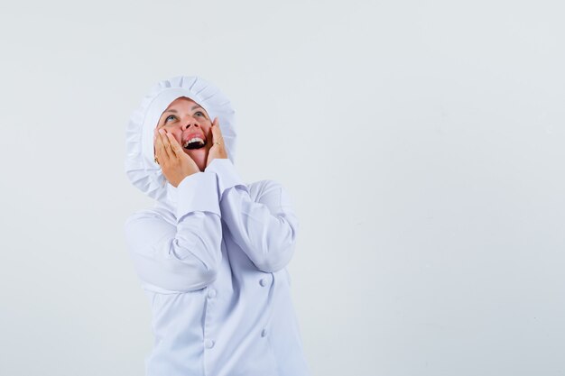 chef donna alzando lo sguardo con le mani sul viso in uniforme bianca e cercando lo spazio contento per il testo