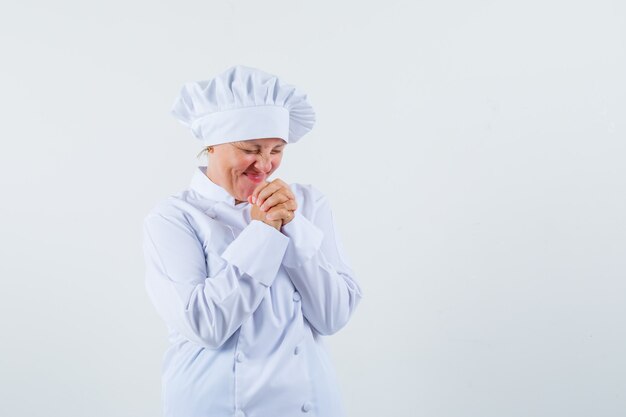 chef donna che desidera in uniforme bianca e sembra speranzosa.