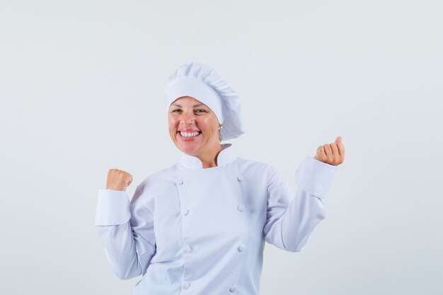 chef donna che mostra il gesto del vincitore in uniforme bianca e che sembra allegra.