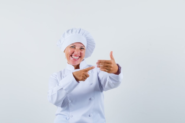 chef donna che punta alla lista in uniforme bianca e che sembra allegra