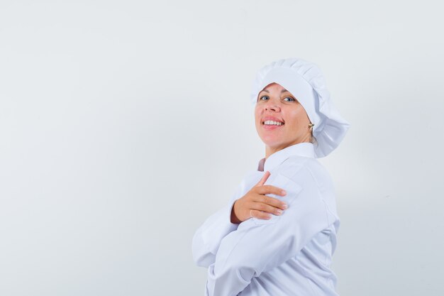 chef donna in piedi con le braccia incrociate in uniforme bianca e guardando fiducioso