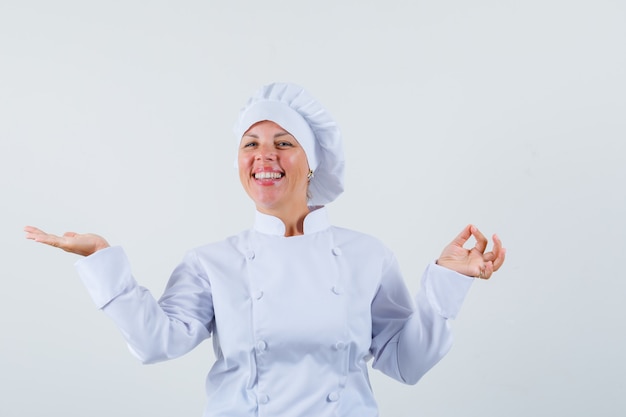 chef donna in uniforme bianca che mostra il gesto giusto mentre diffonde il palmo aperto da parte e sembra ottimista