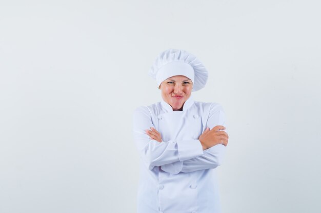 chef donna in uniforme bianca in posa con le braccia incrociate e sembra allegra