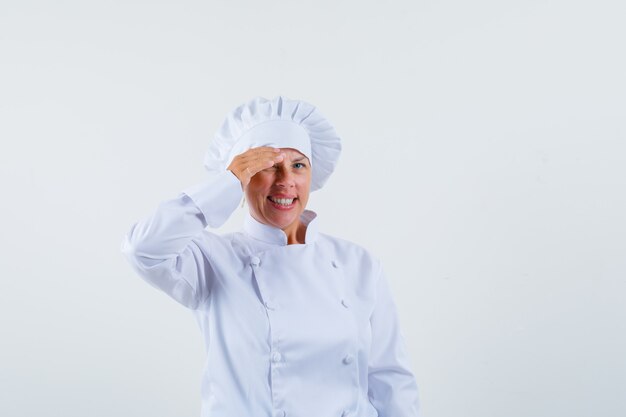 chef donna tenendo la mano sulla fronte in uniforme bianca e annoiata