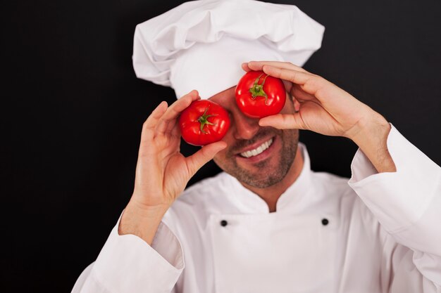 Chef felice che copre gli occhi di pomodori