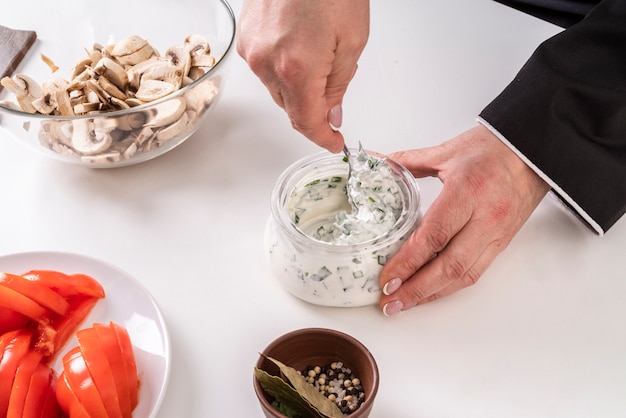 Chef mescolando salsa con funghi e pomodori