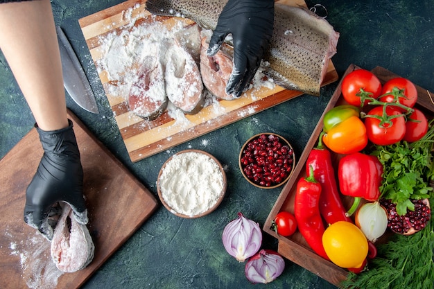 Chef vista dall'alto che copre fette di pesce con farina di verdure fresche su tavola di legno ciotola di farina sul tavolo da cucina