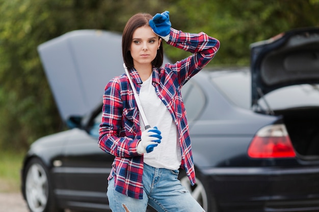 Chiave della tenuta della donna con l'automobile nel fondo