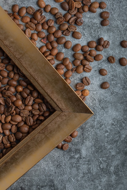 Chicchi di caffè con cornice vuota su una superficie di marmo.