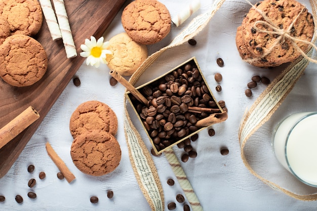 Chicchi di caffè e biscotti al burro con un bicchiere di latte.