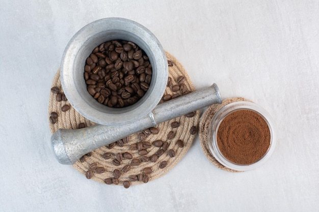 Chicchi di caffè in mortaio e pestello con cacao in polvere