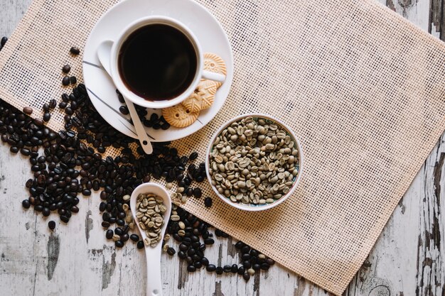 Chicchi di caffè non torrefatti e tazza di caffè