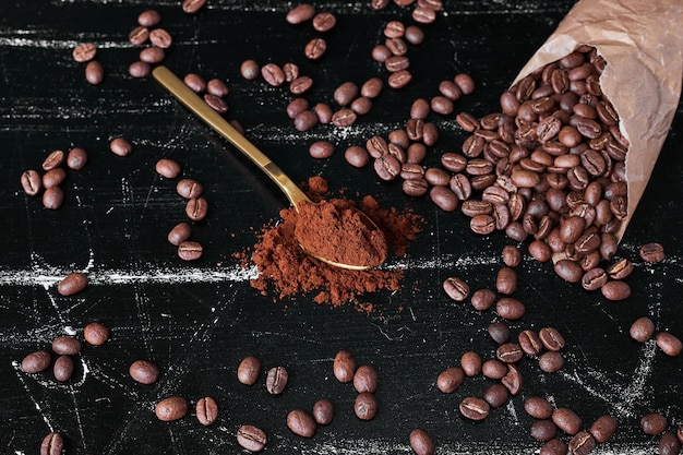 Chicchi di caffè su sfondo nero con polvere.