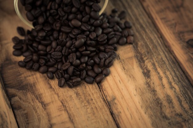 Chicchi di caffè su un tavolo di legno che esce da una ciotola