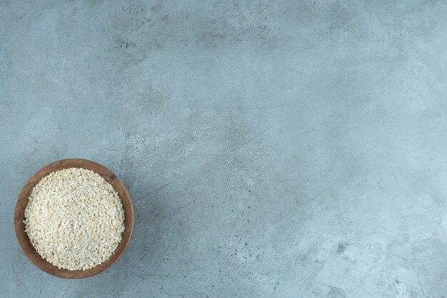 Chicchi di grano o riso in una tazza di legno su sfondo blu. Foto di alta qualità