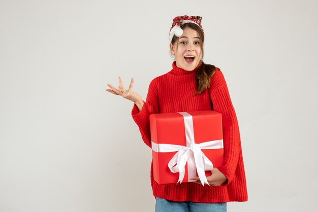 chiedendo ragazza con cappello santa tenendo presente in piedi su bianco