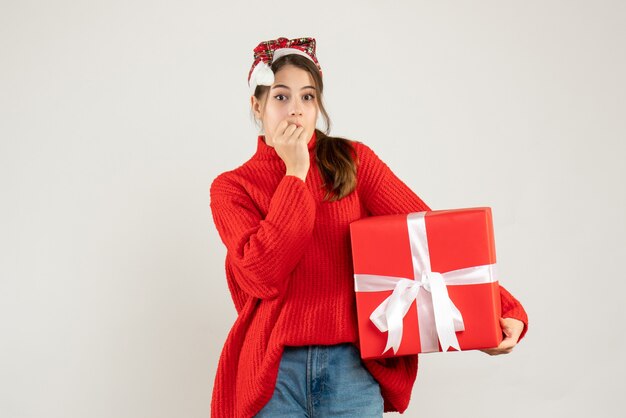 chiedendo ragazza con cappello santa tenendo presente mettendo la mano sulla bocca in piedi su bianco