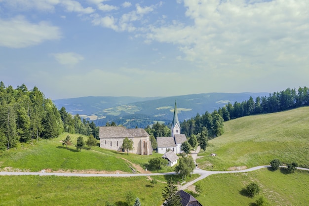 Chiesa di Lese in un campo circondato da colline coperte di verde in Slovenia