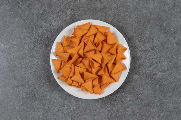 Chip a forma di triangolo sul piatto bianco.